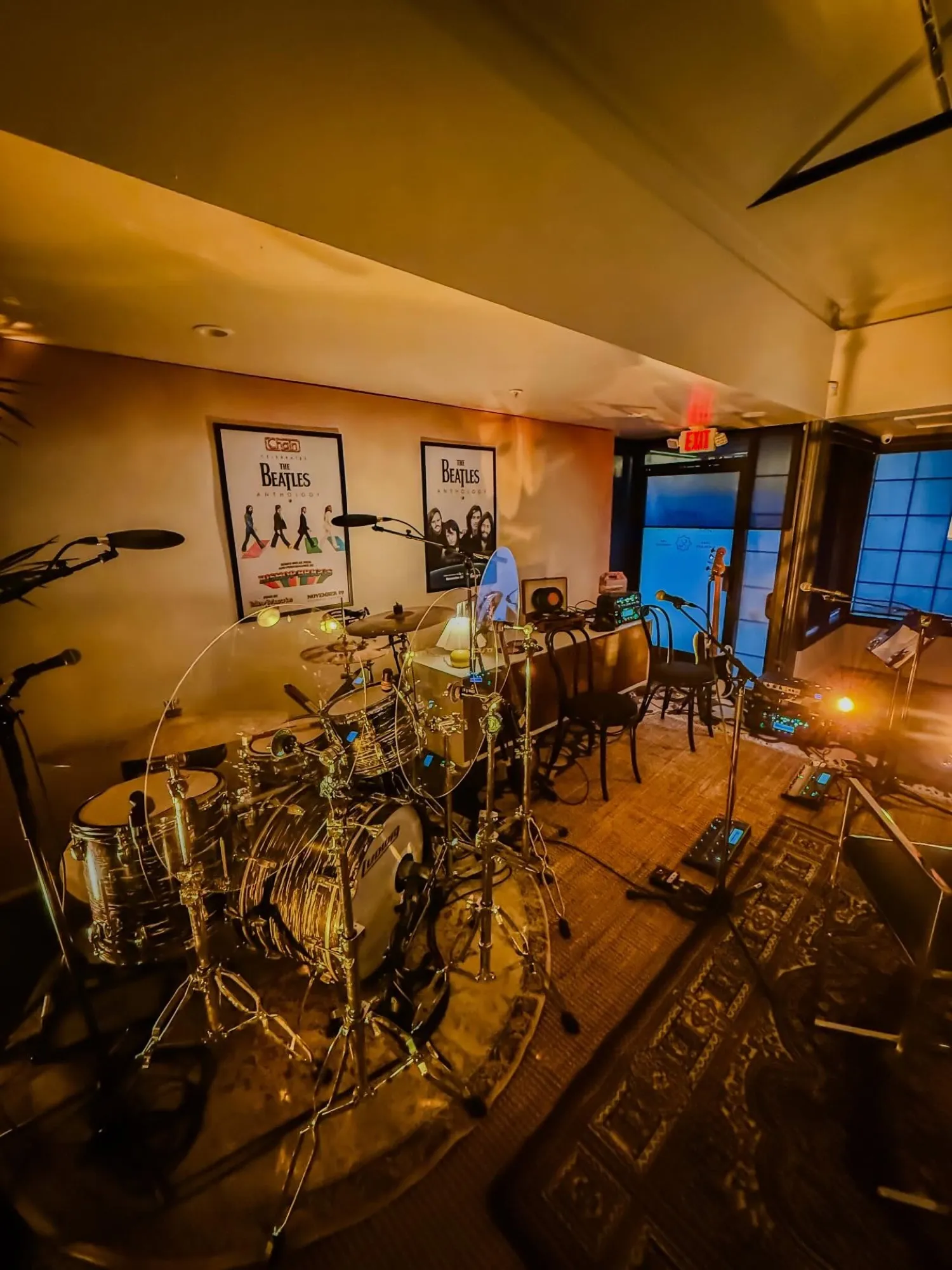 A miked-up gold-sparkle drum kit in a warm Beatles-themed listening room.