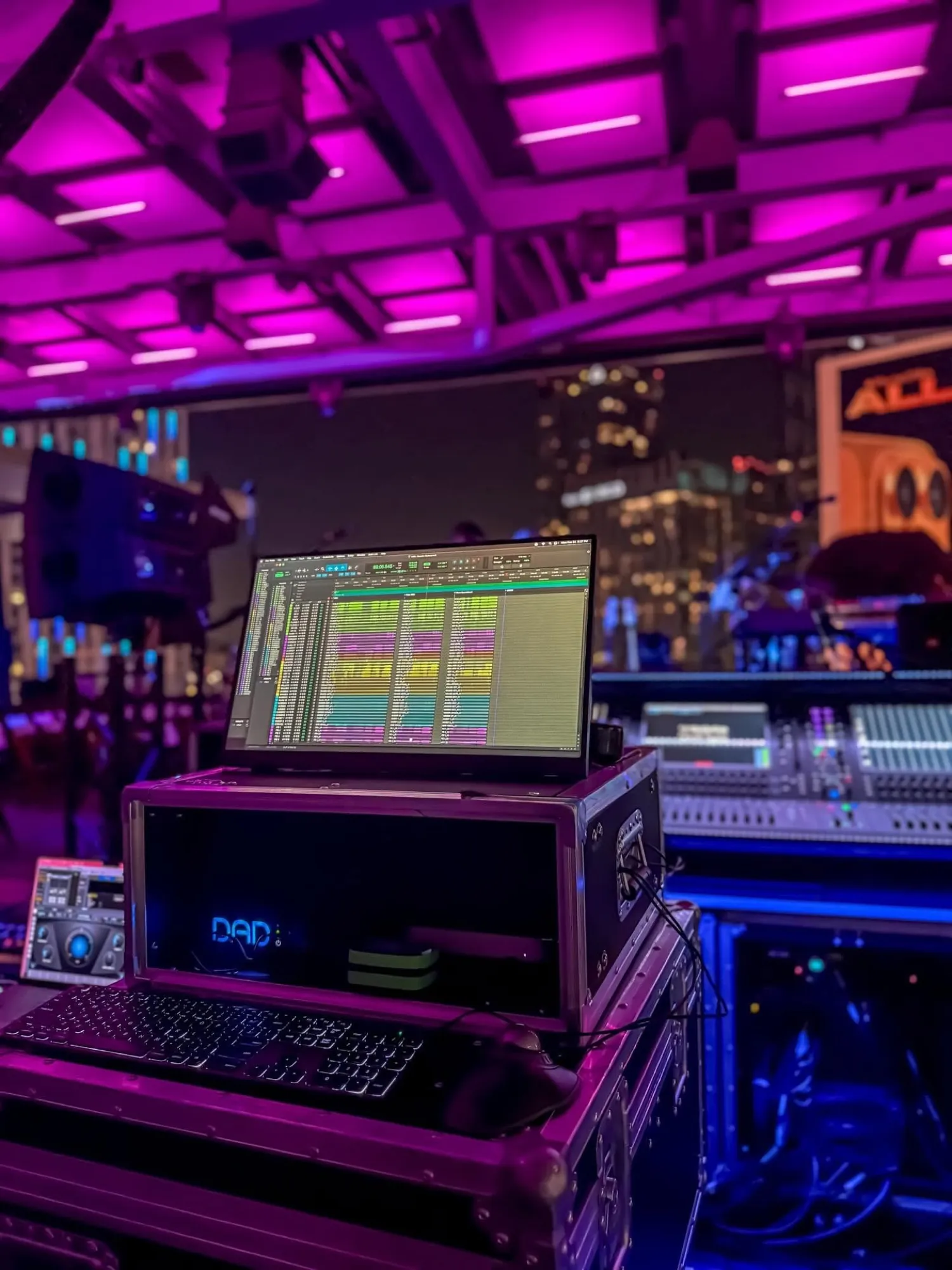 A DAD interface and laptop running a session at a rooftop event, magenta ceiling and the lit Los Angeles skyline behind.
