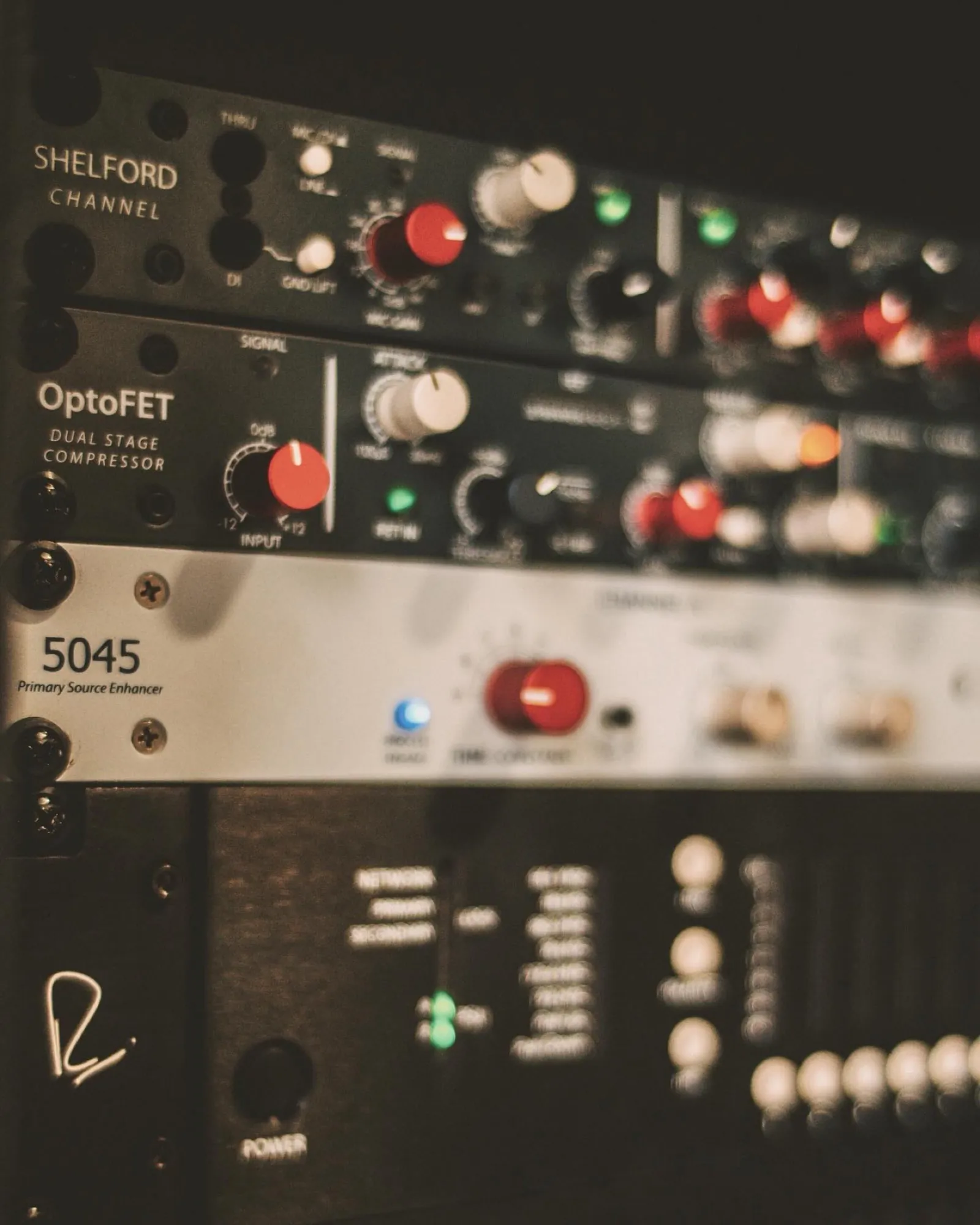 A shallow-depth macro of a Rupert Neve Shelford Channel and an OptoFET compressor in a rack, warm metering glowing.